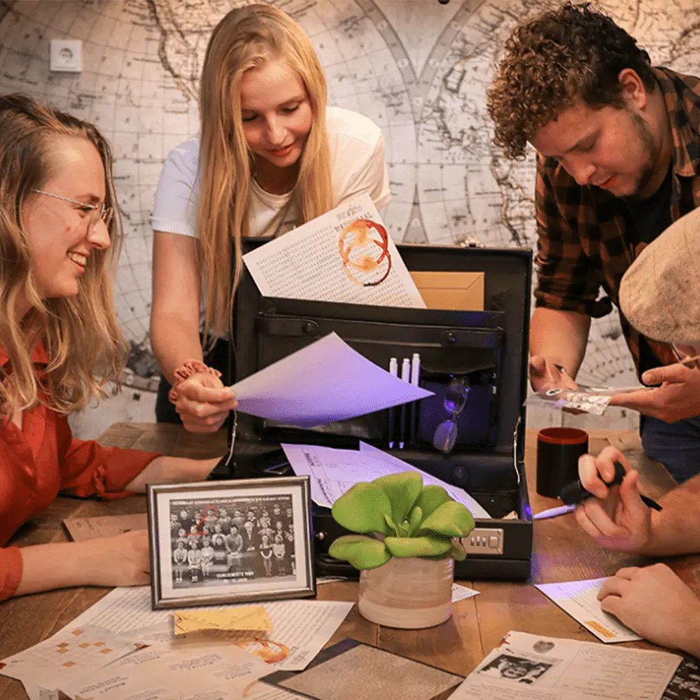 Team lost samen een escape game op: vier collega's onderzoeken documenten en aanwijzingen in een koffer onder UV-licht
