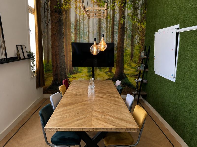 De Bos-ruimte bij STOOM Apeldoorn met een grote houten vergadertafel, scherm en whiteboard