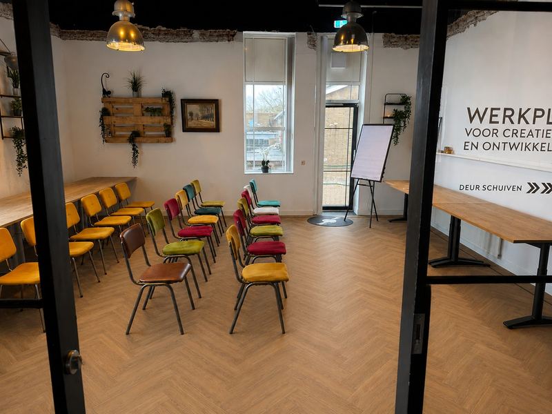 De Werkplaats bij STOOM Apeldoorn, ingericht met stoelen, werktafels langs de wand en een flipover